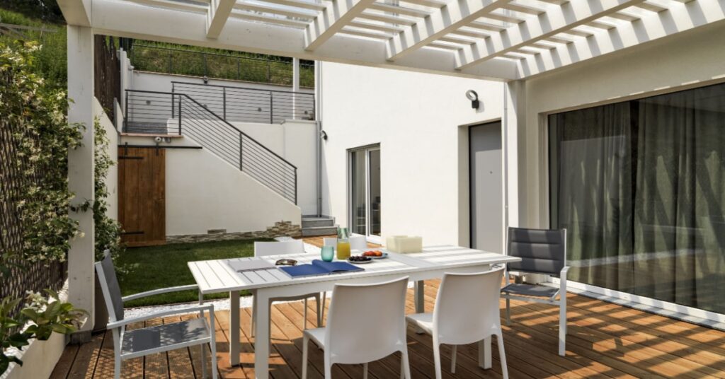 pergola terrasse en bois blanc avec table de jardin et chaises blanches