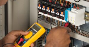 mains d'un electricien en train de vérifier le courant d'un circuit électrique