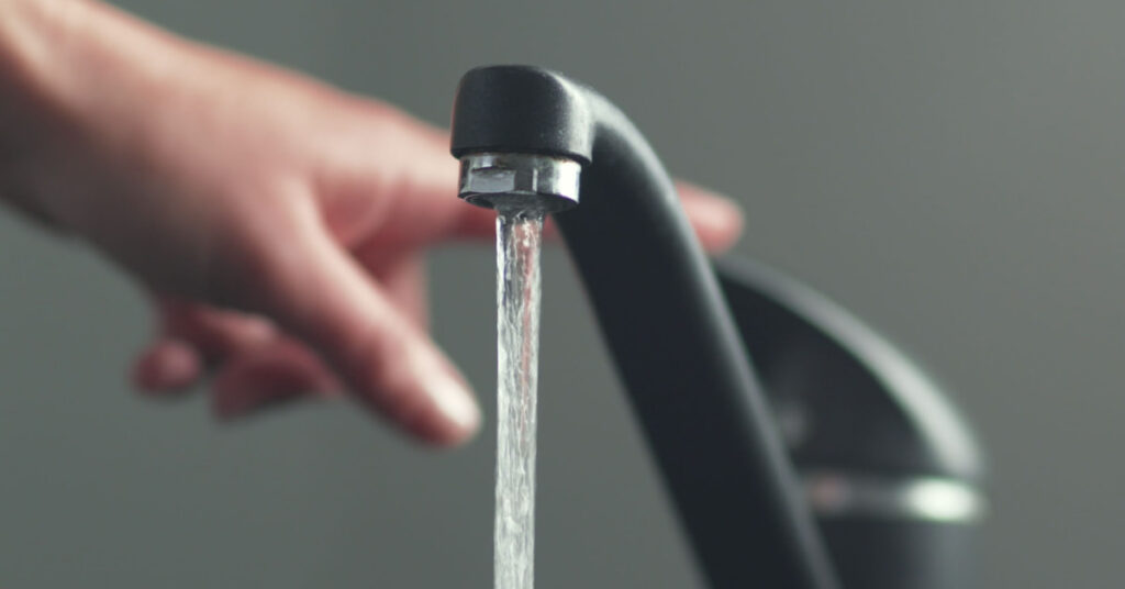 Gros plan sur une main qui actionne un robinet d'eau domestique. 