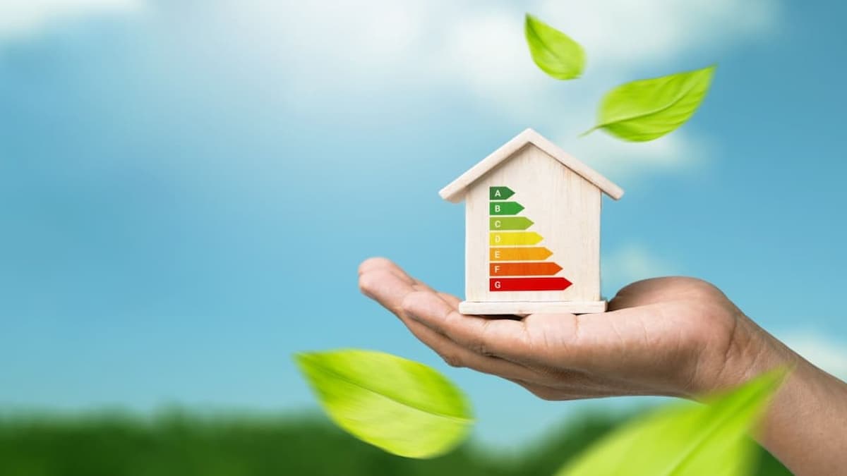 Une main tient une petite maison en bois en bas qui représente l'écologie