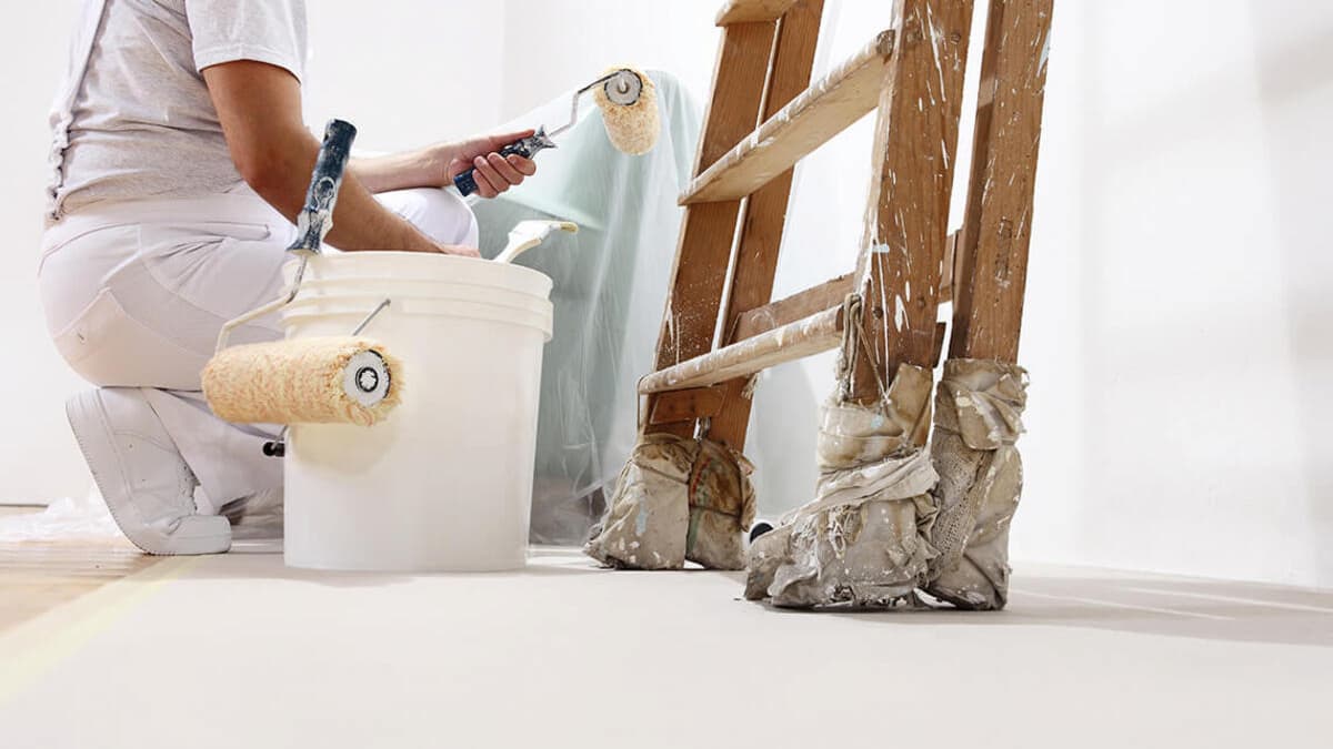 Une personne en train de peindre les murs intérieurs d'une maison en blanc 